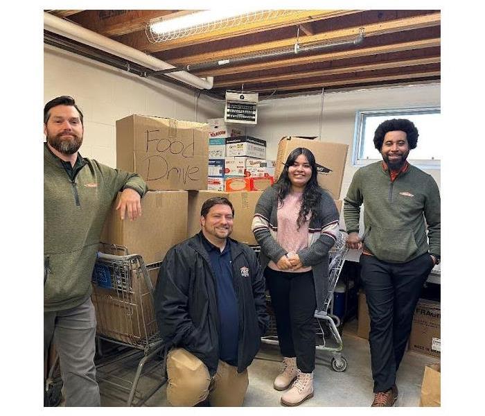 servpro team and cupboard employee with donations